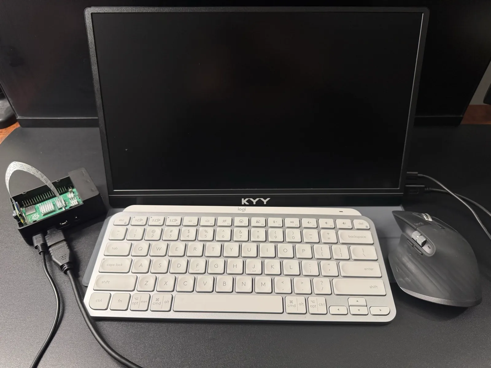 Raspberry Pi cabled to a portable monitor, with a keyboard and mouse on the desk in front